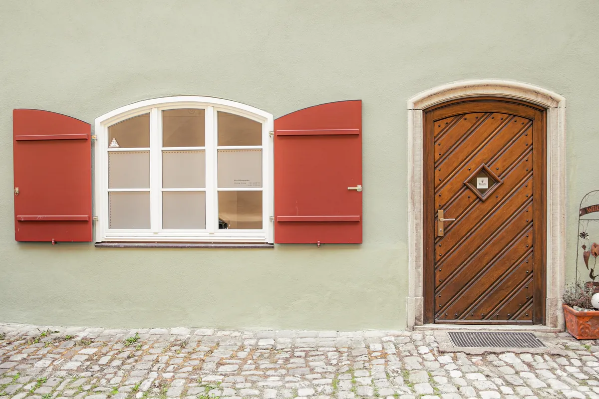 Spitalgasse 3: grüne Fassade, rote Fensterläden, alte Holztür